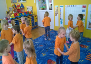 Dzieci tańczące w parach na dywanie.